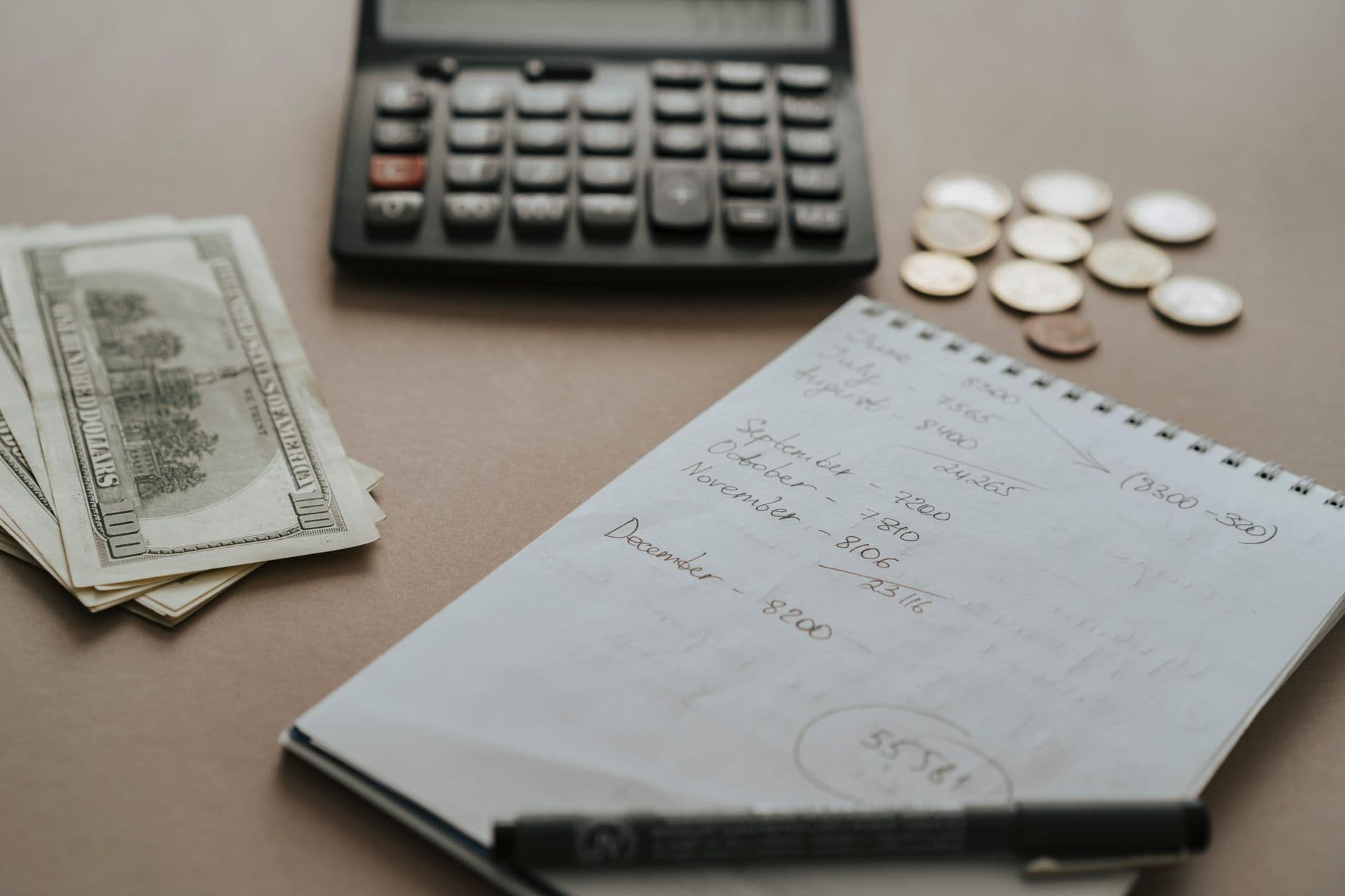 Calculadora, dinheiro e caderno de anotações sobre uma mesa