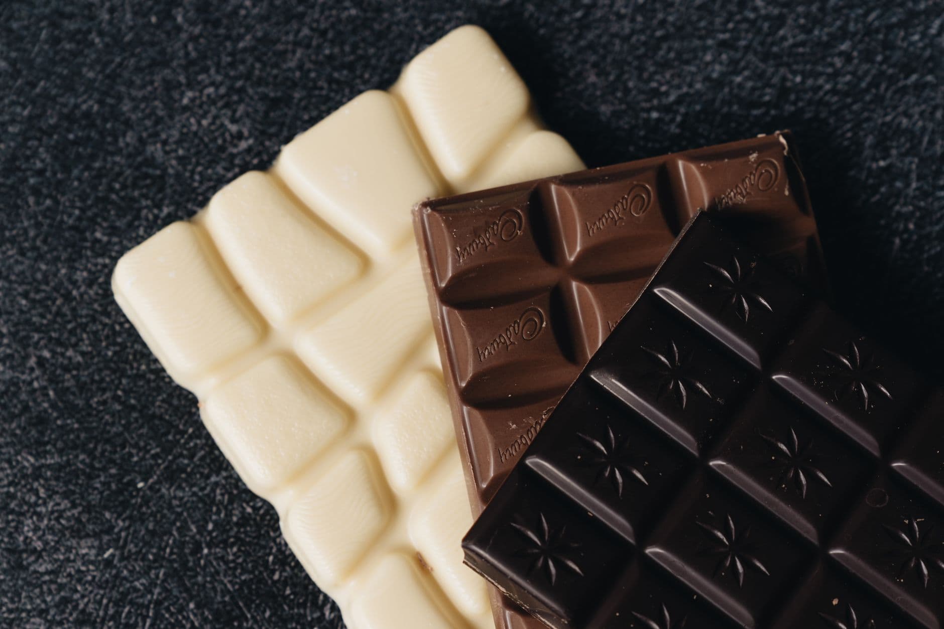 barras e pedaços de chocolate ao lado de chocolate derretido