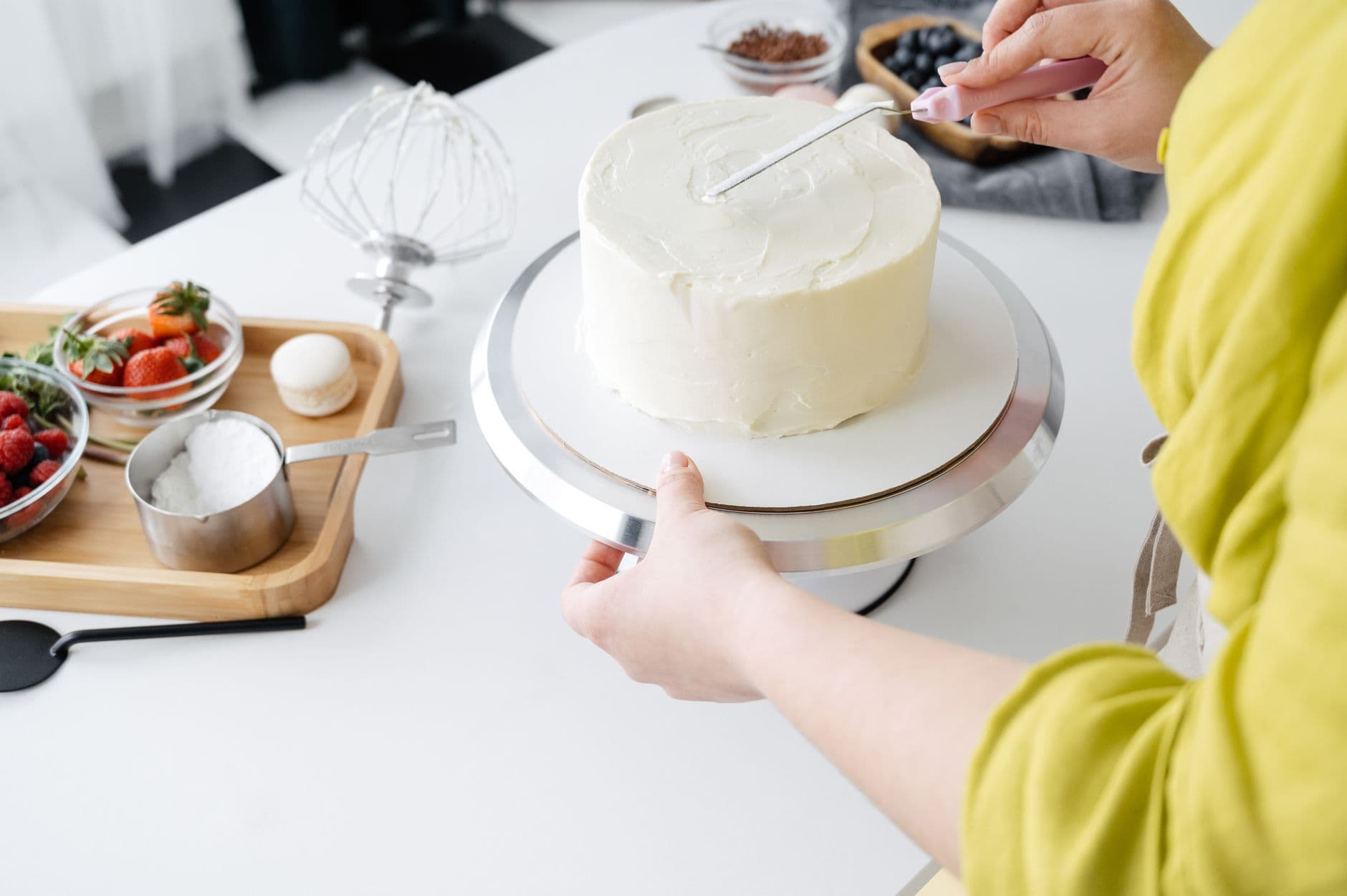 confeiteira decorando um bolo na bancada da cozinha
